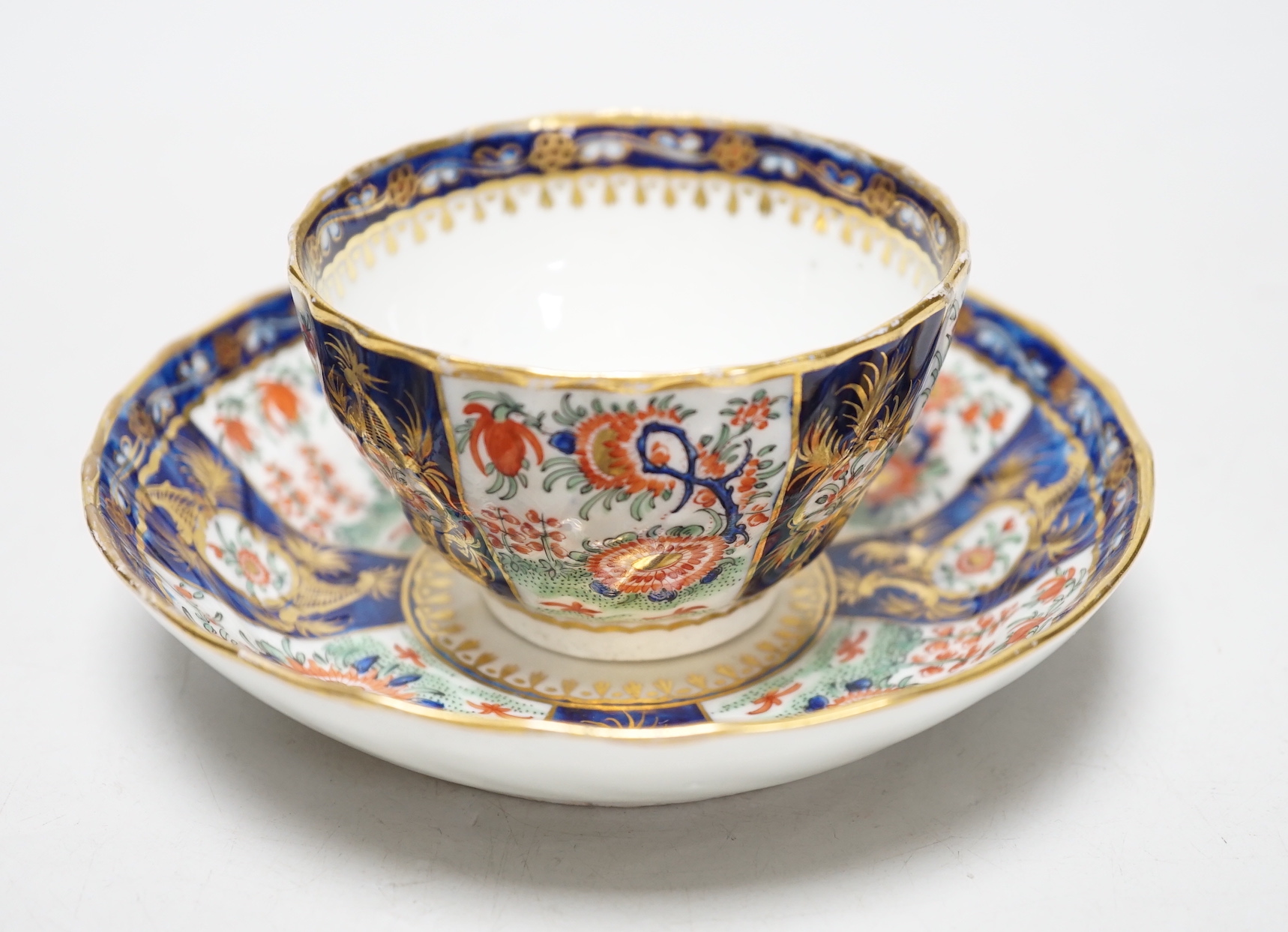 A Chamberlains Worcester good kakiemon style teabowl and saucer painted with oriental flowering plants in fan shaped panel, c.1785-90